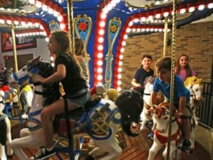 Kids riding iPlay america's Carousel during extended Spring Break hours!